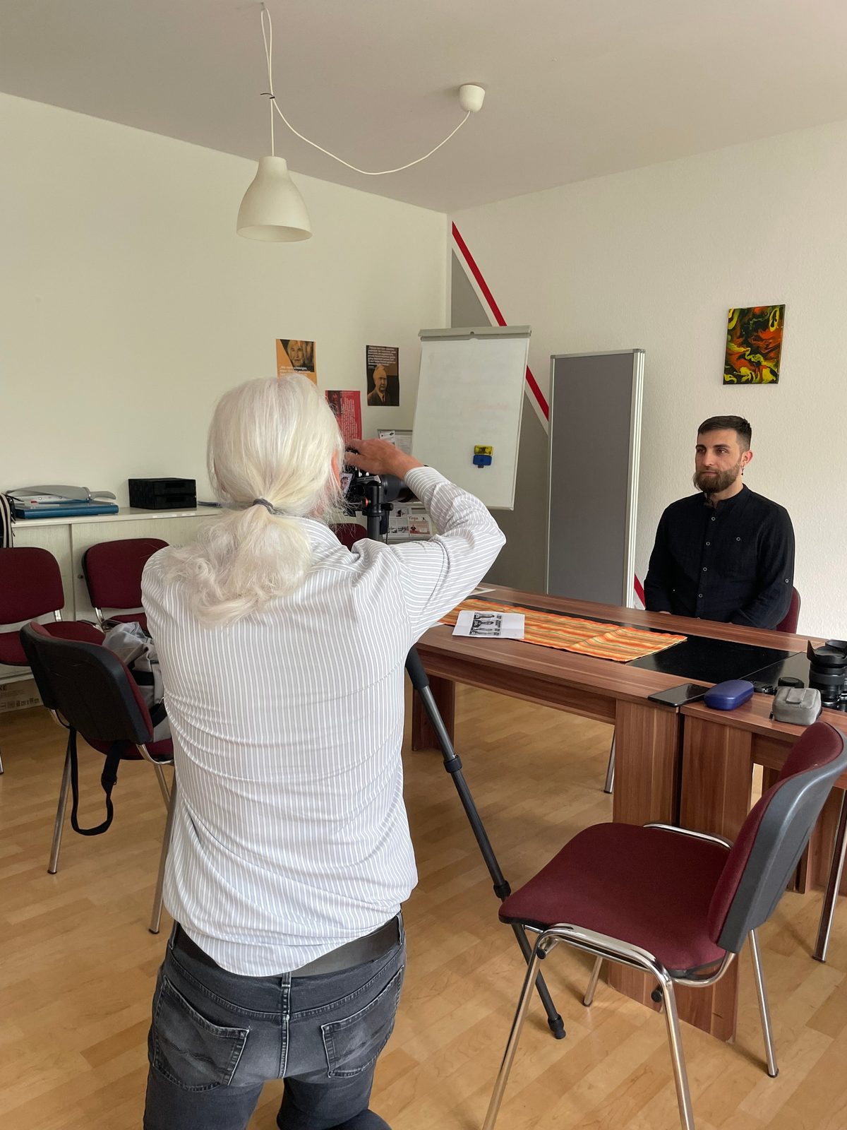 Fotoshooting für die Ausstellung: Eine Fotografin porträtiert einen Mann in einem Büroraum.