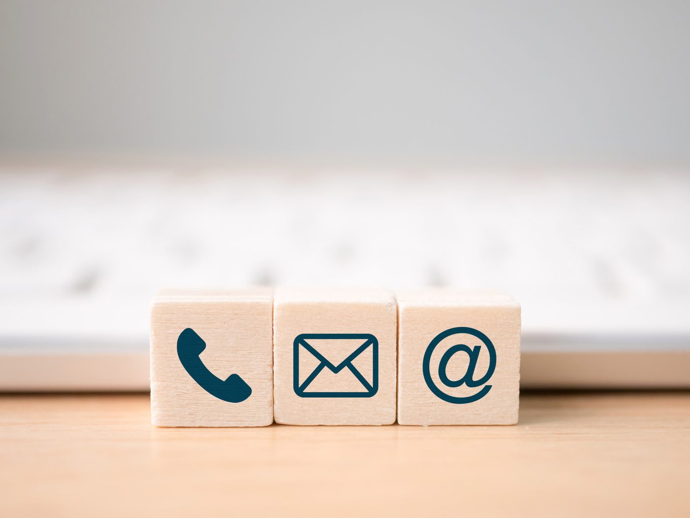 Holzwürfel mit Symbolen für Telefon, Brief und E-Mail.